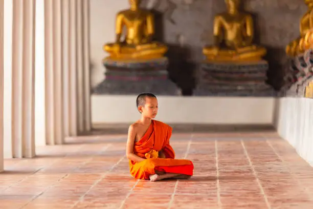 Photo of Young novice monk sitting for meditation at Wat Phutthaisawan temple, Ayutthaya