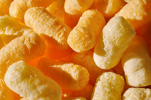 Closeup of puffcorn under sunlight. Sweet snack corn puffs. Macro of puffed corn.