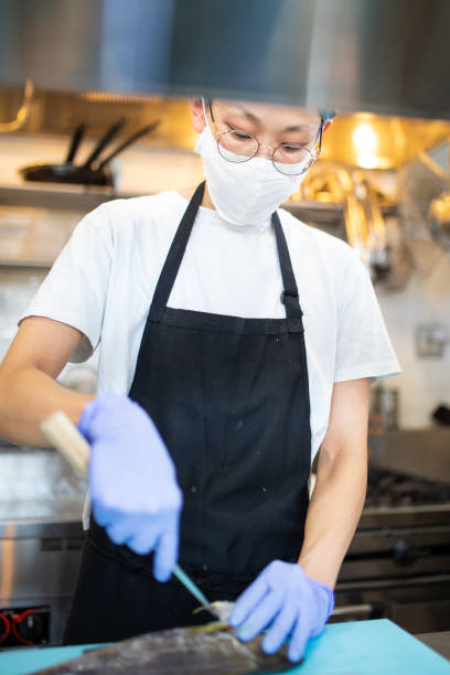 istock Japanese female chef fish preparation in a cafe kitchen 1332040793