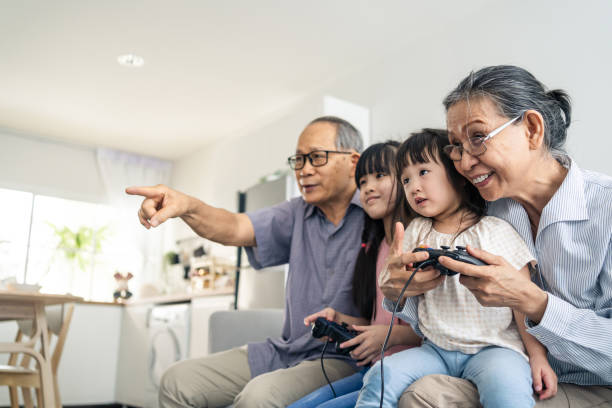 asian happy family stay home grandparent play game with little girl. loving senior elder older couple play video games in front of television with young children granddaughter in living room together. - gamer watching tv adult couple imagens e fotografias de stock