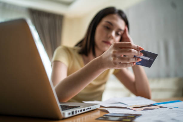 Depressed Asian young girl feel worry about financial problem in house. Stressed desperate young woman looking frustrated to paperwork and bills think of money debt, budget loss, bankruptcy at home. stock photo