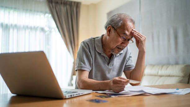 istock Depressed Asian Senior Elderly male feel worry about financial problem. Stressed desperate older man looking frustrated to paperwork and bills think of money debt, budget loss, bankruptcy at home. 1332045438