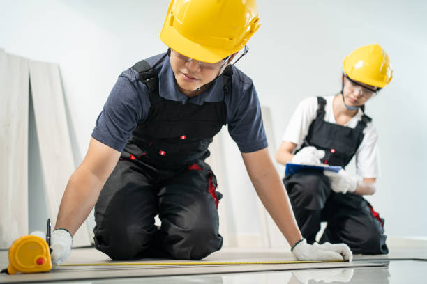 istock Asian construction worker male use tape measure parquet on corridor. Joiner builder woman help and support Craftman work to repair and installs laminate board on floor to renovate house apartment. 1332045657