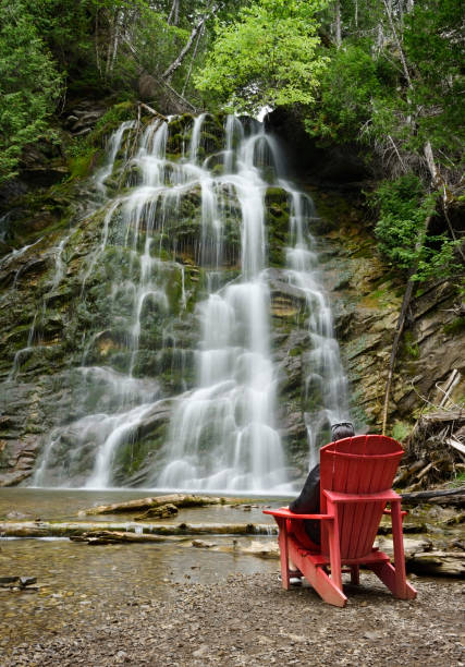 Relaxation at the waterfall Woman relaxing in red outdoor adirondak chair contemplating waterfall forillon national park stock pictures, royalty-free photos & images