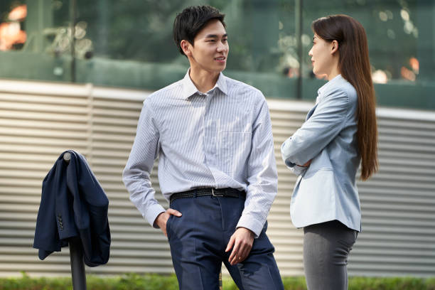 istock two asian office workers standing on city street chatting 1332054894