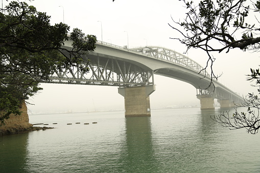 A side view of the Auckland harbour bridge on an overcast day.