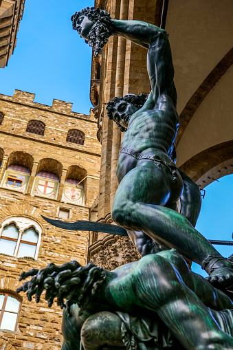 The magnificent bronze statue of Perseus who raises the head of Medusa after cutting it, by Benvenuto Cellini and preserved in the Loggia Dei Lanzi, in Piazza della Signoria, in the historic heart of Florence, in Tuscany. Commissioned and strongly desired by Duke Cosimo de Medici, the statue of Perseus represents the cutting of every republican ambition of the city and the end of the ancient political divisions. According to mythological legend, Perseus killed Medusa by cutting off her head through the reflection on her shield, avoiding being petrified by her gaze. The Loggia dei Lanzi, an open structure with arch and columns designed by the architects Benci and Simone Talenti in 1376 on the right side of Piazza della Signoria, was used for the official ceremonies of the Florentine government. On background the Palazzo Vecchio. Since 1982 the historic center of Florence has been declared a World Heritage Site by Unesco. Image in high definition format.