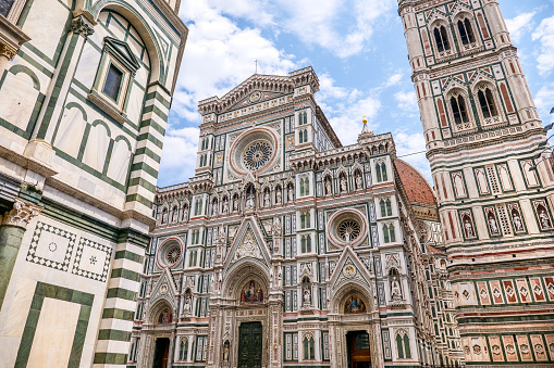 A stunning view of the facade of the Cathedral of Santa Maria del Fiore, or simply the Duomo of Florence, with the majestic bell tower by Giotto (right), in the historic heart of Florence, in Tuscany. Built starting from 1296 on a project by the medieval architect Arnolfo di Cambio, the Florentine Cathedral was definitively finished and consecrated in 1436, after the completion of the majestic dome designed by the Florentine architect Filippo Brunelleschi. The construction of the magnificent bell tower was begun in 1298 and finished in 1359 under the direction of Giotto di Bondone. The Duomo, visited every year by tens of thousands of tourists, is the third largest cathedral in Europe, after St. Peter's Basilica in Rome and St. Paul's Basilica in London. Since 1982 the historic center of Florence has been declared a World Heritage Site by Unesco. Image in high definition format.