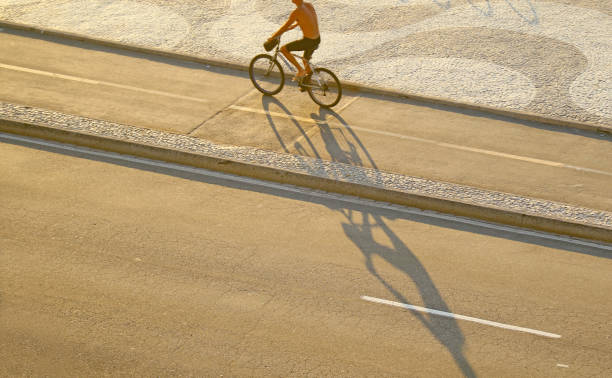 uomo in bicicletta lungo il marciapiede a onde, spiaggia di copacabana a rio de janeiro, brasile - brazil bicycle rio de janeiro outdoors foto e immagini stock