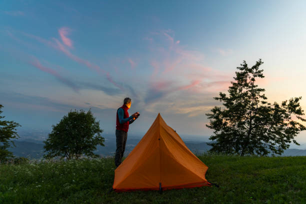 Hiker checking smartphone app during camping solo