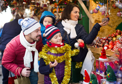Charming parents with children customer near counter with Christmas decoration