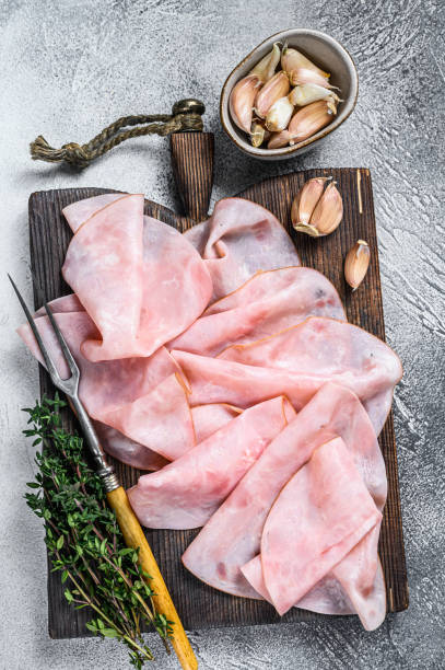 istock Ham Thin sliced on wooden cutting board with herbs. White background. Top view 1332072126