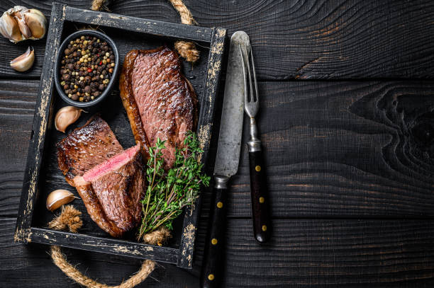 barbecue grilled rump cap or brazilian picanha beef meat steak in a wooden tray. black wooden background. top view. copy space - picanha beef meat rare imagens e fotografias de stock