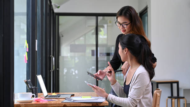 istock Two business woman using smart phone together in office. 1332073353