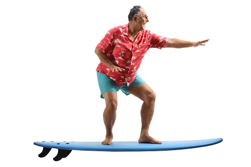 Full length shot of a mature man riding a surfing board isolated on white background