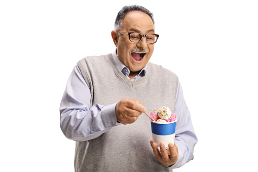 Happy mature man eating ice cream in a paper cup isolated on white background