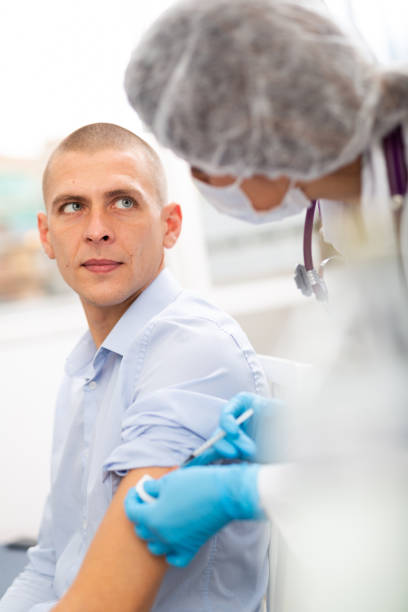 istock doctor in a protective face mask makes vaccination 1332074474