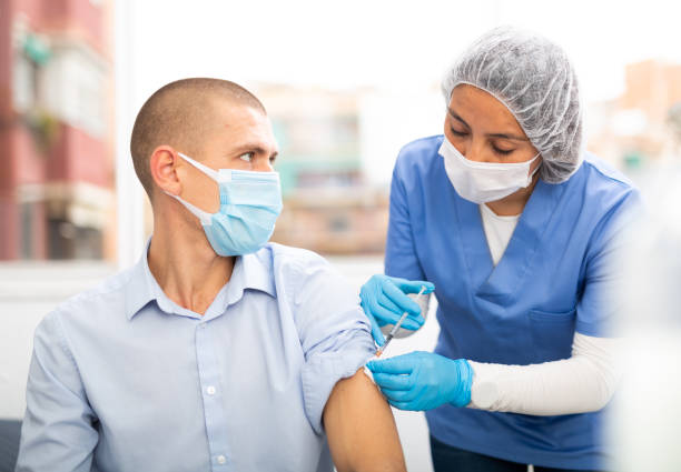 istock Professional nurse giving vaccine injection to man 1332074476