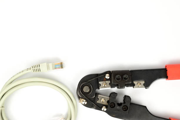 istock Tool for crimping network wires. Nearby lies a rolled-up patch cord 1332076116