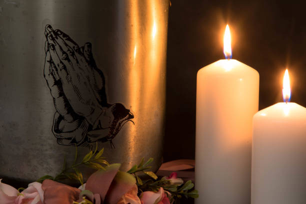 Sympathy card. Funeral urn with praying hands and burning candles. Metal urn with ashes of a dead person on a funeral. Sad grieving moment at the end of a life. Last farewell and grief concept. End of Life cricket trophy stock pictures, royalty-free photos & images