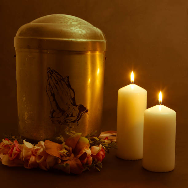 Sympathy card. Funeral urn with praying hands and burning candles. Metal urn with ashes of a dead person on a funeral. Sad grieving moment at the end of a life. Last farewell and grief concept. End of Life cricket trophy stock pictures, royalty-free photos & images