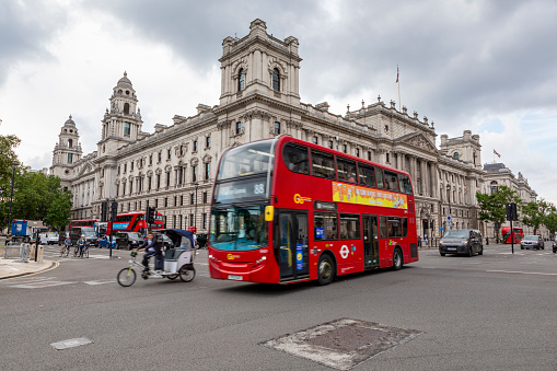 London, UK - Jul 27, 2021:M odern Red bus and urban cyclists in motion on the busy streets of London