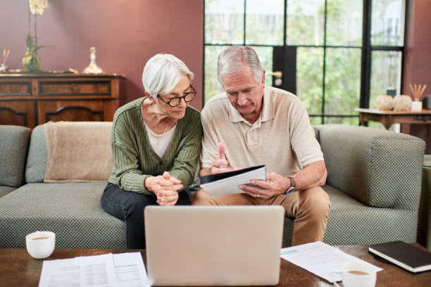 istock Shot of a senior couple using a laptop while going through paperwork at home 1332084810