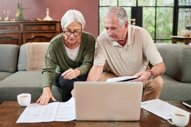 istock Shot of a senior couple using a laptop while going through paperwork at home 1332084811