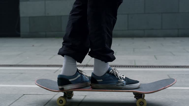 Unrecognizable man feet balancing on skateboarding on city street closeup.