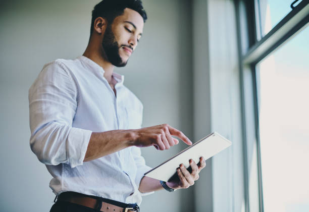 istock Shot of a young businessman using a digital tablet in a modern office 1332087003