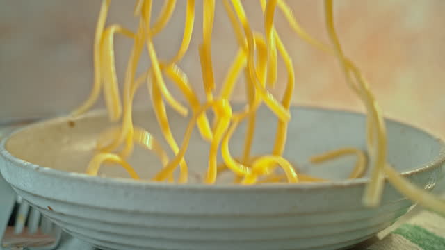 SLO MO LD Pasta falling onto a plate