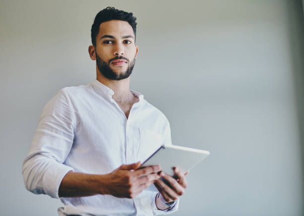 istock Shot of a young businessman using a digital tablet against a grey background in a modern office 1332087155