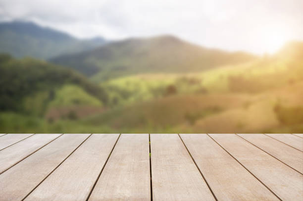 istock Empty old wooden table in front of blurred beautiful mountain and meadow with beautiful sunrise background of nature. Can be used for display or montage for show your products. 1332087249