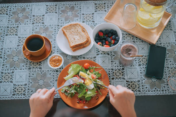 directamente por encima de la vista de ángulo alto asiático chino mitad adulto mano disfrutando de un desayuno saludable en el comedor - salad breakfast cooked eggs fotografías e imágenes de stock