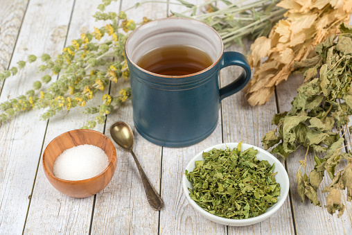 Green tea or herbal tea with cup, sugar and dry herbs