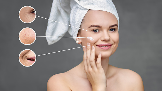Happy young woman applying moisturizing anti aging cream on face – Smiling natural female using ecological cosmetic lotion to remove skin imperfection and wrinkles during beauty routine