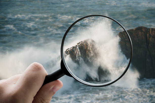istock Magnifying glass focusing on a breaking sea wave 1332092365