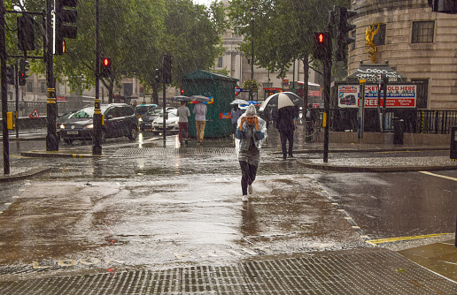 London, United Kingdom - July 28 2021: People run for cover in Trafalgar Square as torrential rain falls.
