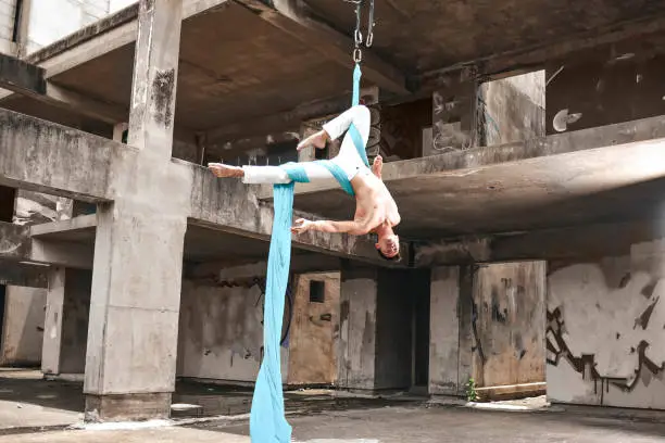 Men doing aerial fabric in abandon building. An Aerialist doing inversion.