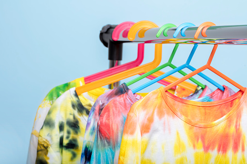 Colorful Tie Dye long sleeved shirts hanging on hangers on a rack. Tie Dye patterns were created by the photographer.