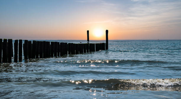 Peaceful and romantic background with breakwaters on the beach at sunset.