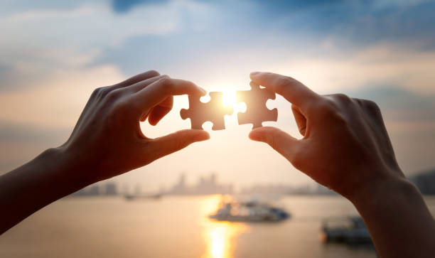 Human hands put two jigsaw puzzle pieces together Human hands put two jigsaw puzzle pieces together. things that go together stock pictures, royalty-free photos & images