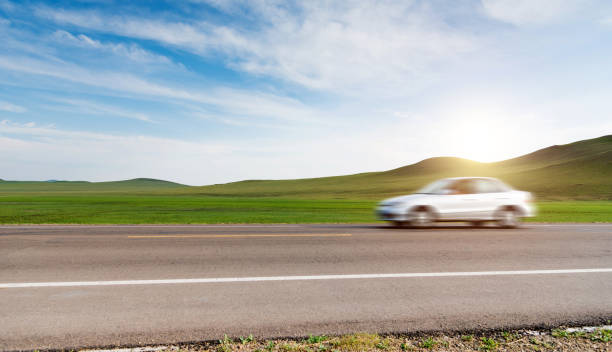 istock White car driving on grassland highway 1332097281