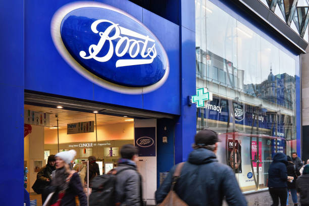 blue oval sign at one of many boots branches in london - retail london england uk people imagens e fotografias de stock