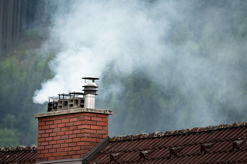 Smoke coming out of an old chimney, cloudy day in summer
