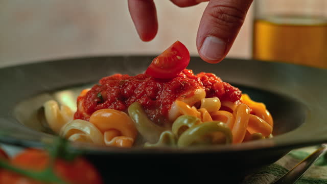 SLO MO Adding a cut cherry tomato onto pasta