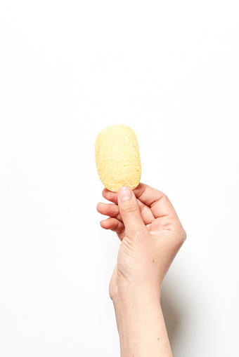 Person hand holds a potato chips over white background