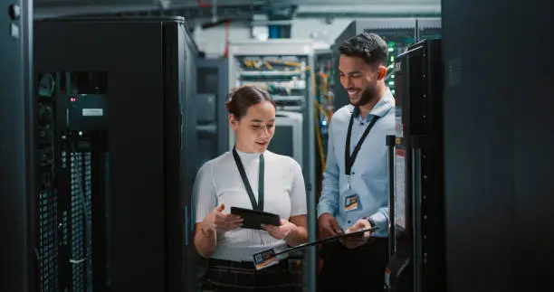 Photo of Shot of two colleagues working together in a server room