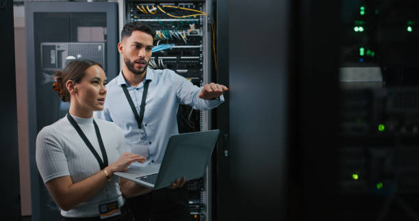 scatto di due colleghi che lavorano insieme in una sala server - tecnico foto e immagini stock