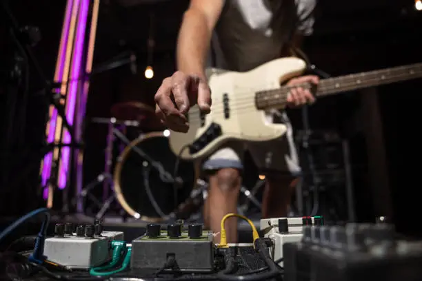 Bass guitar player on a stage with set of distortion effect pedals.